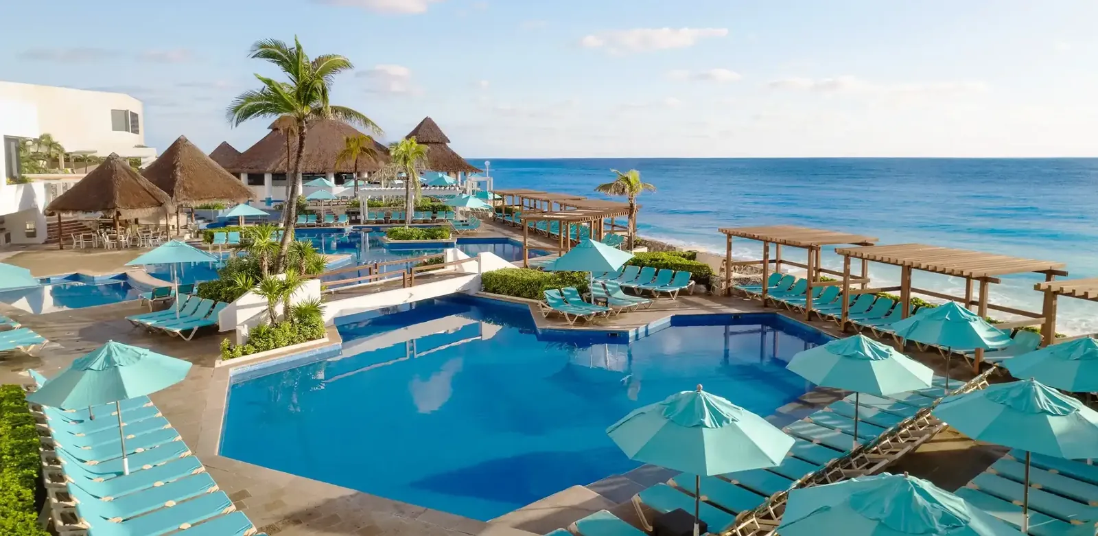 Alberca de Royal Solaris Cancún con palapas y sombrillas frente al Mar Caribe
